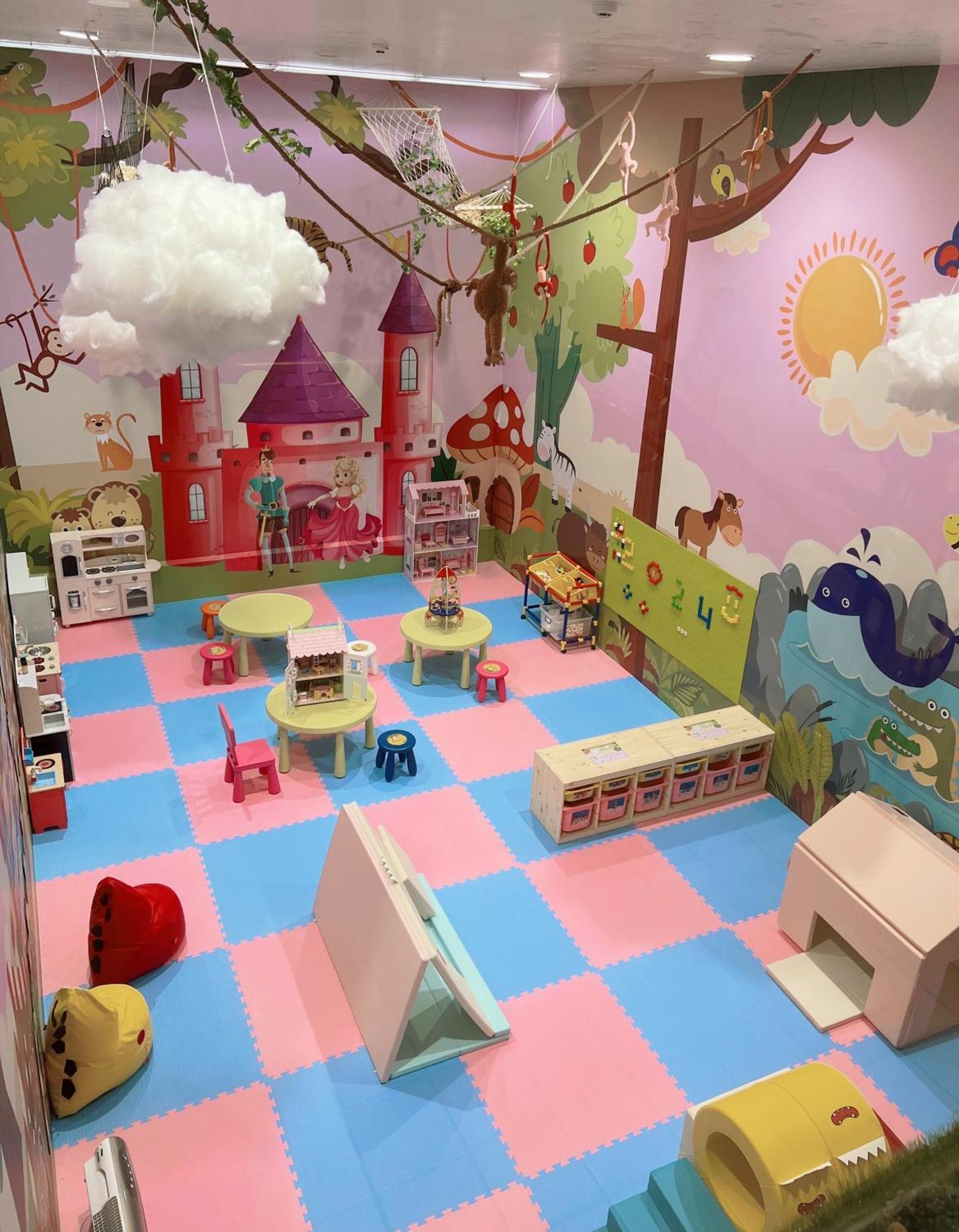 Evergreen Laurel Hotel - Taichung Exterior foto The photo shows a colorful playroom designed for children. It features a vibrant mural with a fairytale castle, trees, and playful animals on the walls. The floor is covered with interlocking foam tiles in pink and blue, providing a soft play surface