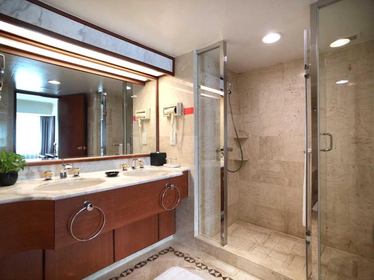 Evergreen Laurel Hotel - Taichung Exterior foto The photo depicts a modern bathroom featuring a double vanity sink with a marble countertop and wooden cabinetry. Above the sinks, there is a large mirror with integrated lighting. To one side, there is a shower enclosed in glass, showcasing a sleek 