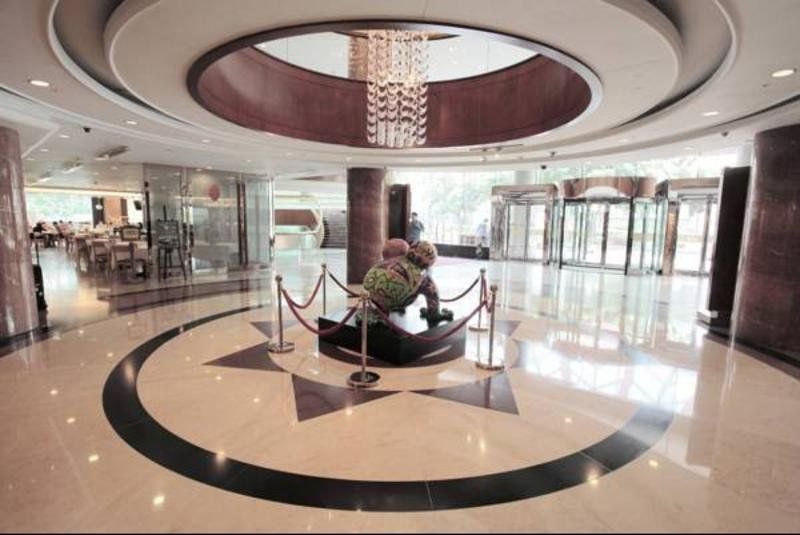 Evergreen Laurel Hotel - Taichung Exterior foto The photo depicts an elegant indoor space, likely the lobby of a hotel or a building. The flooring is made of polished marble tiles, featuring a circular design with contrasting black and light-colored sections. At the center, there is a sculpture su