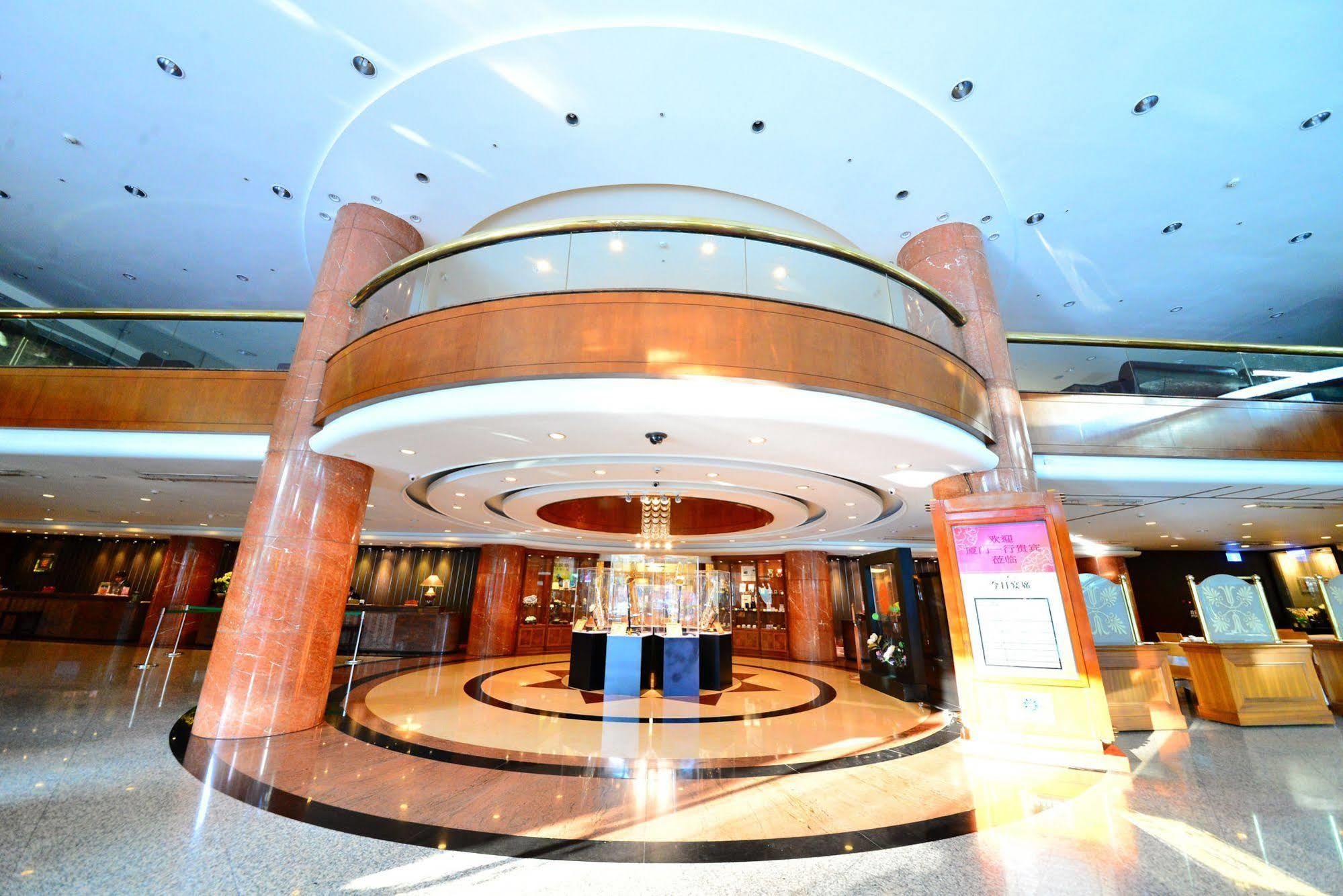 Evergreen Laurel Hotel - Taichung Exterior foto The photo shows the interior of a spacious lobby area. It features a modern architectural design with polished surfaces and a circular ceiling structure. The walls are accented with wooden panels, and there is a central chandelier hanging from the ce