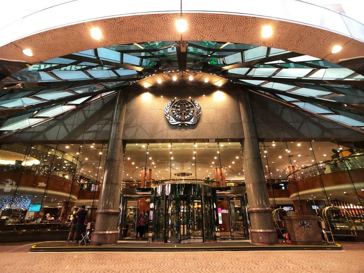 Evergreen Laurel Hotel - Taichung Exterior foto The image shows the entrance of a modern building, likely a hotel or a luxury establishment. The entrance features a large revolving door surrounded by glass panels. Above the entrance, there is a prominent logo or emblem. The overall architectural d
