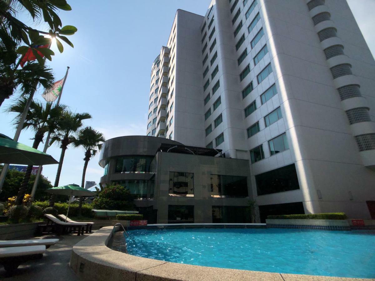 Evergreen Laurel Hotel - Taichung Exterior foto The photo depicts a hotel or residential building alongside a swimming pool. The pool is situated in the foreground, with a curved section of the building visible behind it. Surrounding the pool, there are lounge chairs for relaxation. In the backgro