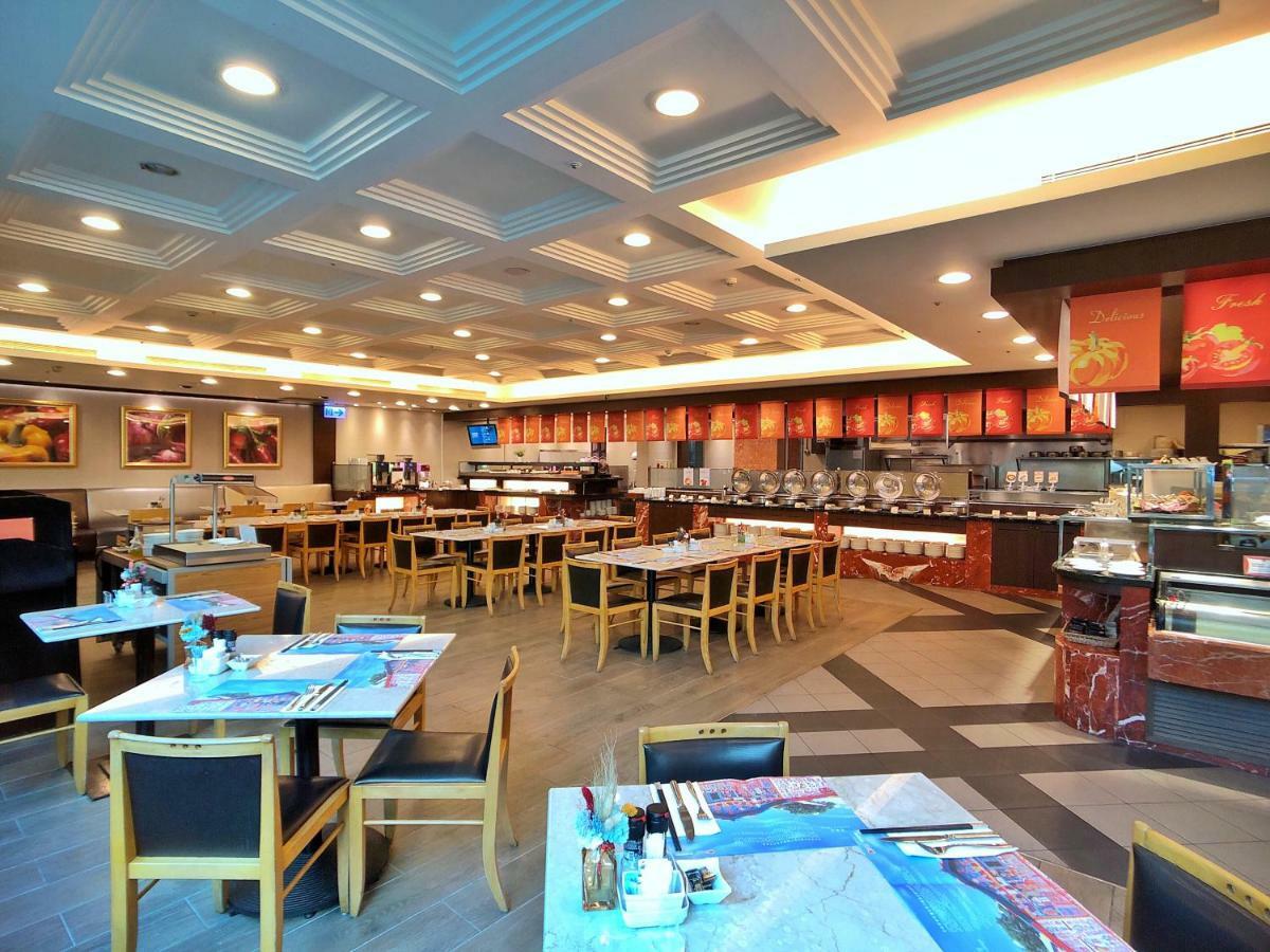 Evergreen Laurel Hotel - Taichung Exterior foto The photo shows the interior of a restaurant. The dining area features several tables with chairs arranged neatly. The flooring has a contemporary design, and the ceiling is structured with a coffered pattern. There is a buffet area along one wall wi